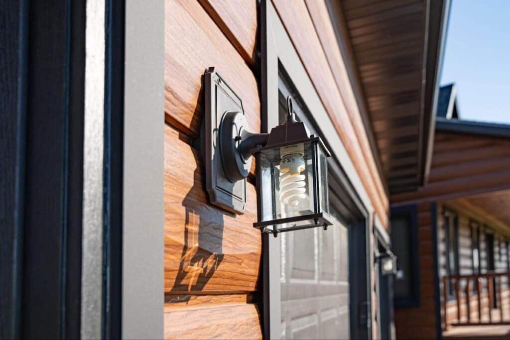 A close up of an exterior wrought iron lanterns mounted on a home with TruLog steel log siding