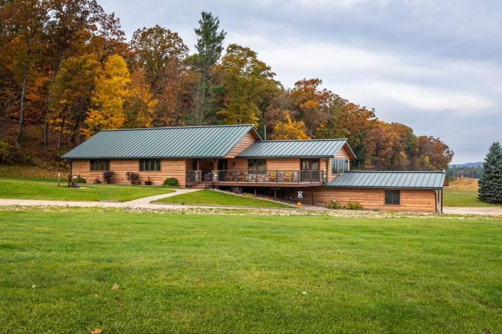 A multi-level home with a green metal roof and wood-look TruLog steel log siding in Hickory