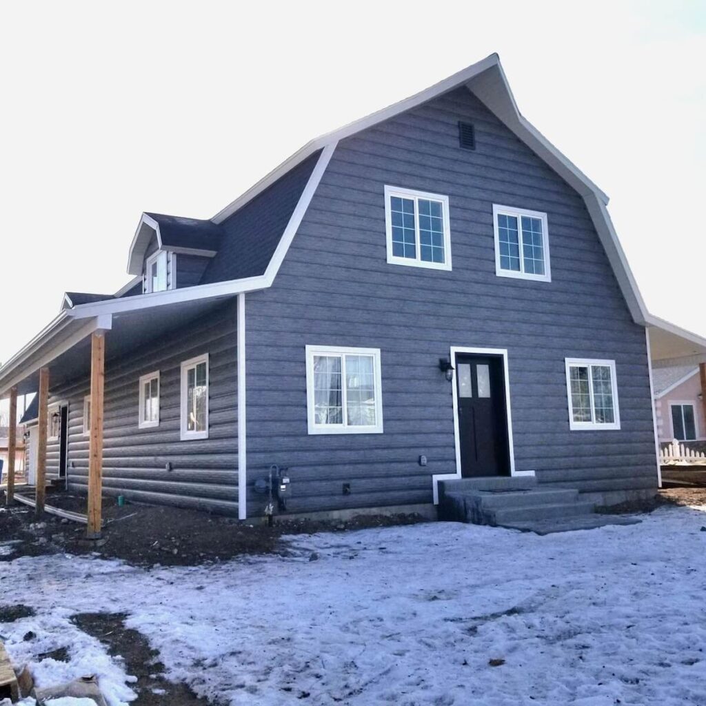 Barndominium with dark gray TruLog steel siding and white trim on a snowy day.