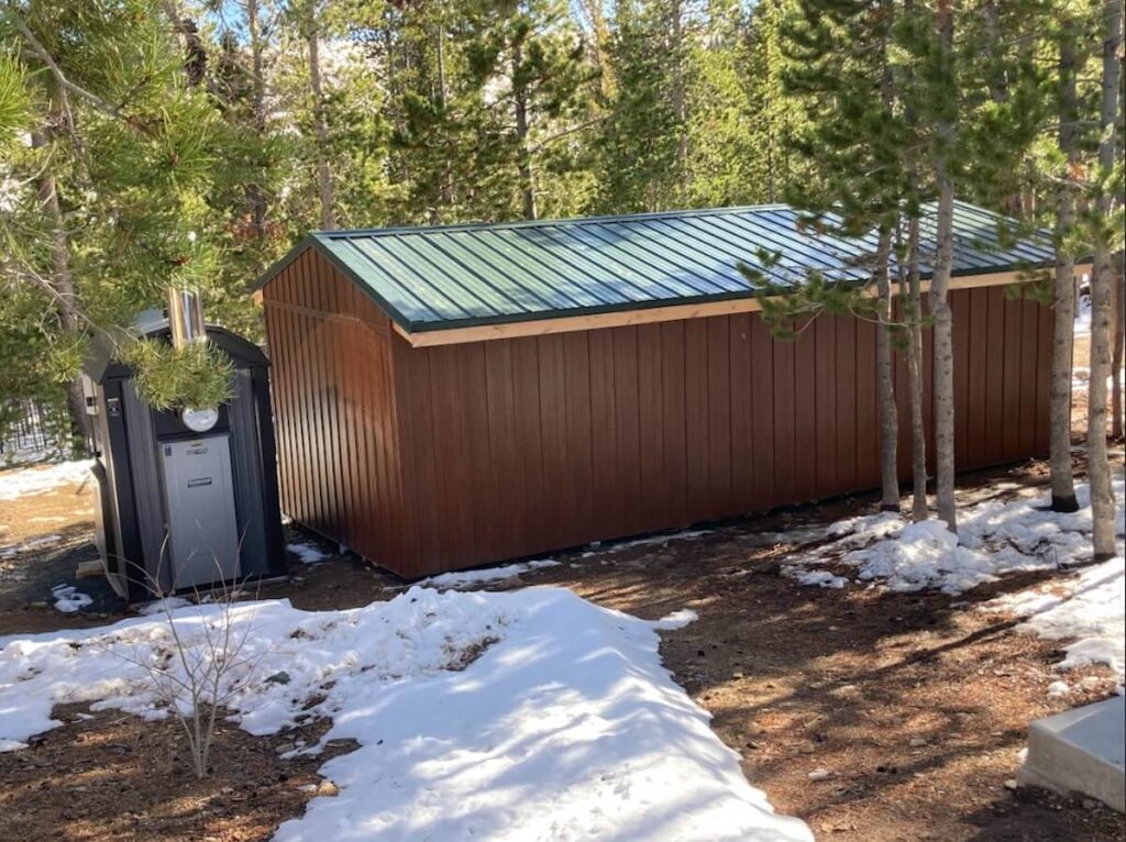 A shed with a green metal roof and TruLog steel board and batten siding