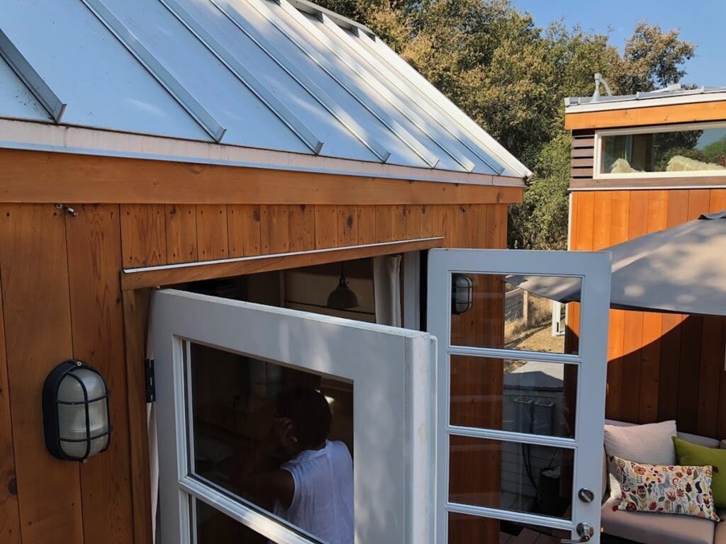 Close-up of a small wood-sided structure with a metal roof and an open door.