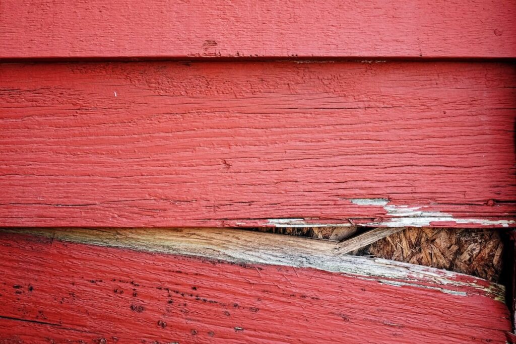 A closeup of a gap between wood siding boards