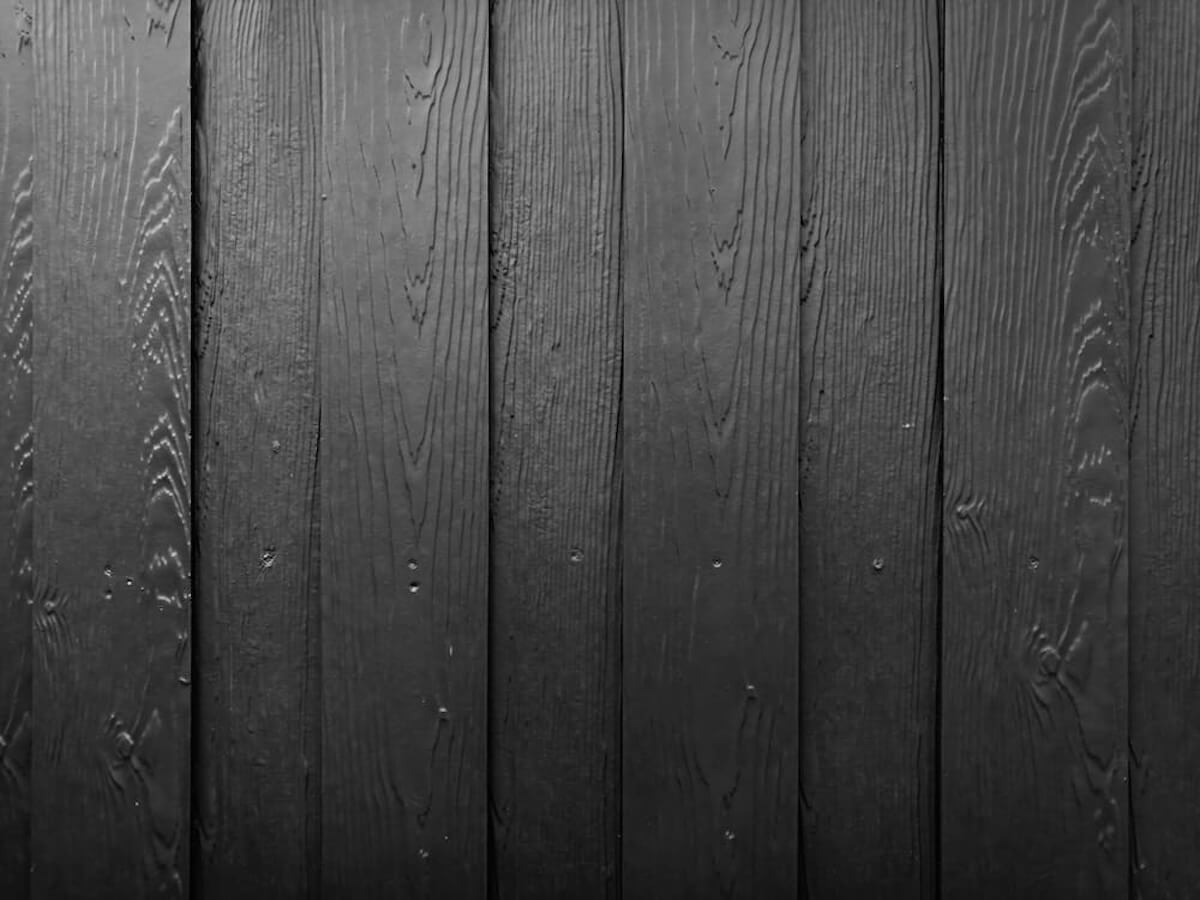 Close-up of dark-stained wood-look plank siding with visible grain texture.