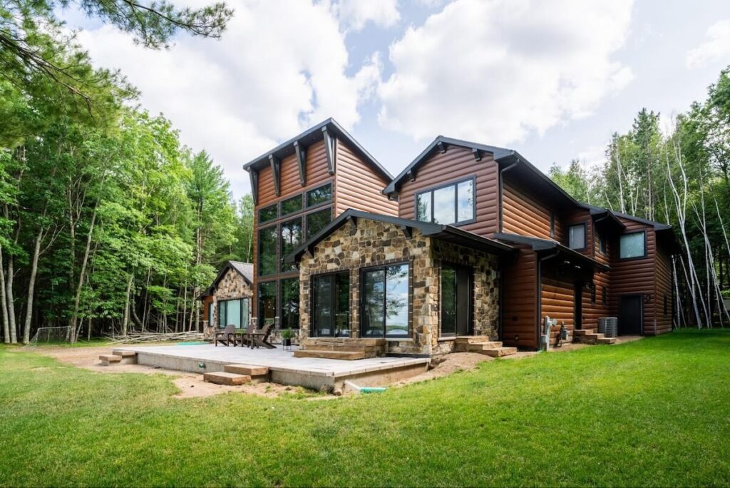 A home with a mix of stone and TruLog steel log siding surrounded by trees