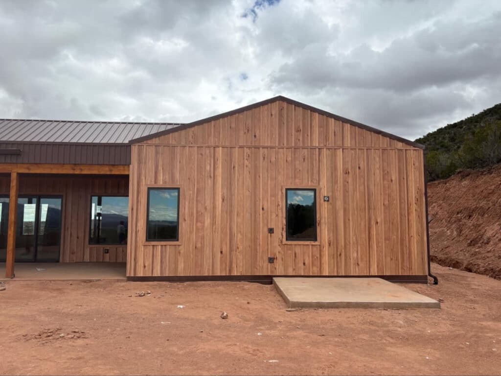 A home with TruLog steel woodgrain board and batten siding under a dark, cloudy sky