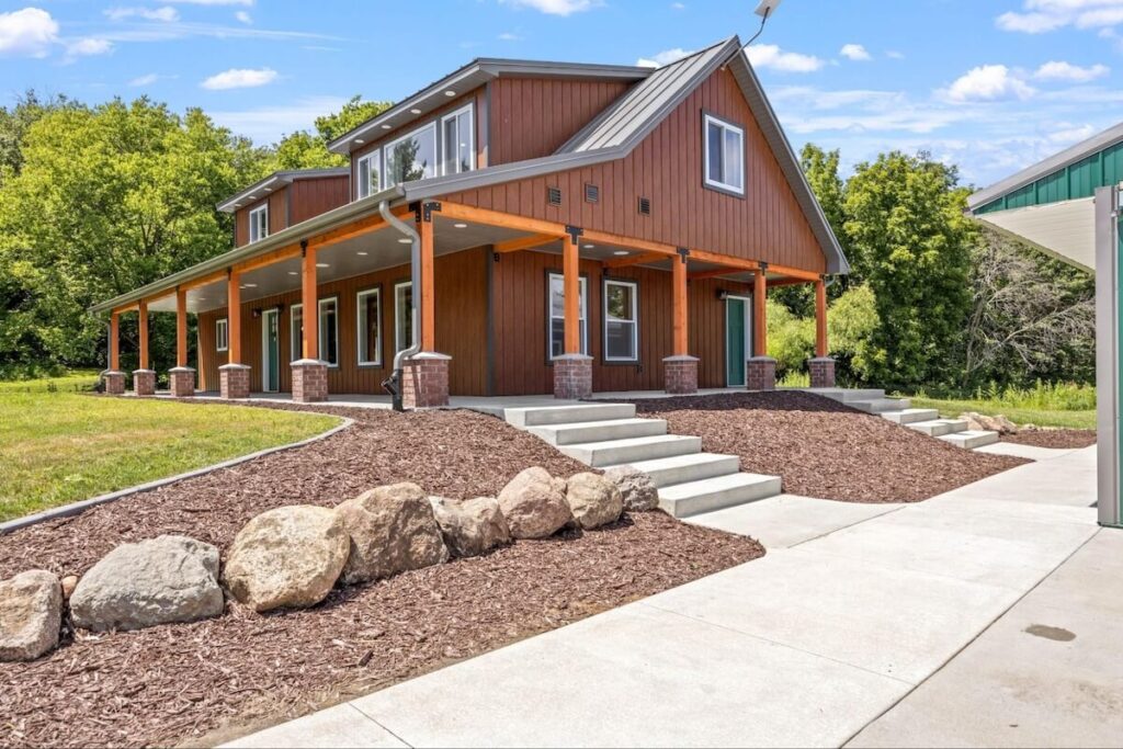 A home that combines a light gray metal roof with TruLog's board and batten siding in Western Cedar