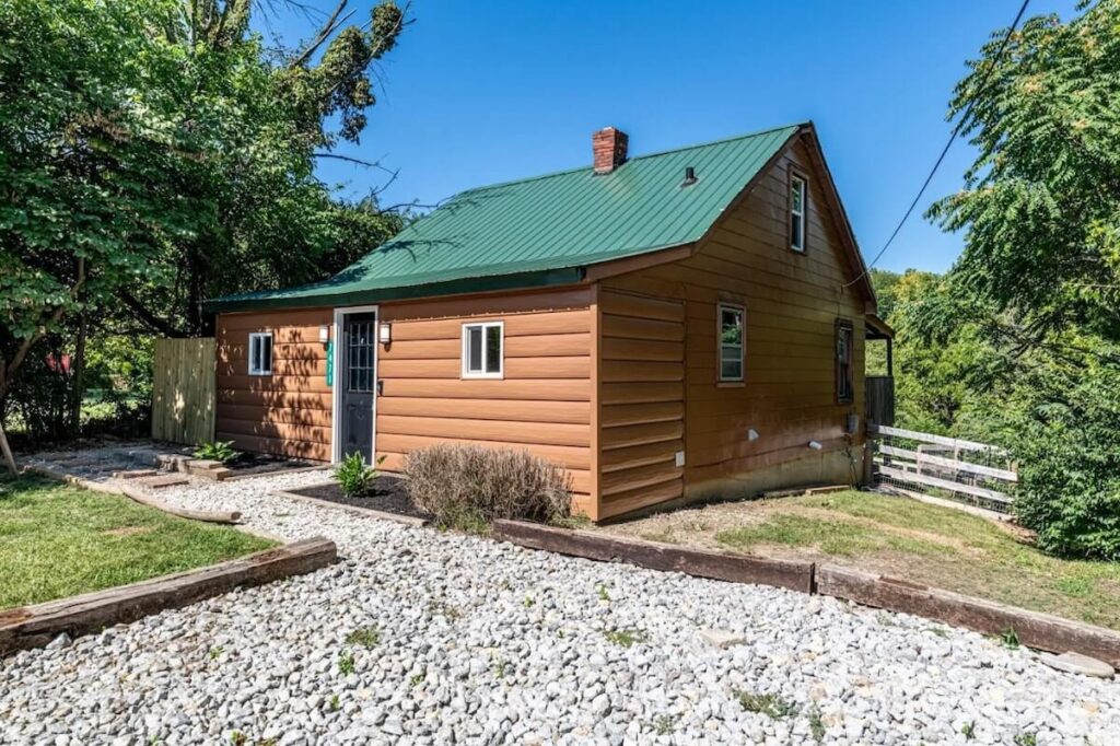 A cabin home with a forest green metal roof and TruLog steel log siding in Standard Cedar