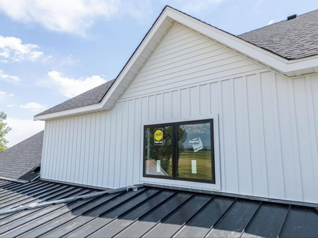 A closeup of the upper level of a modern farmhouse exterior with a combination of TruLog steel lap siding and board and batten siding in Matte White