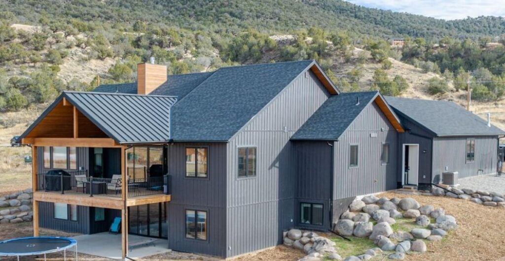 A beautiful home featuring TruLog steel board and batten siding in Dark Charcoal with mountains in the background