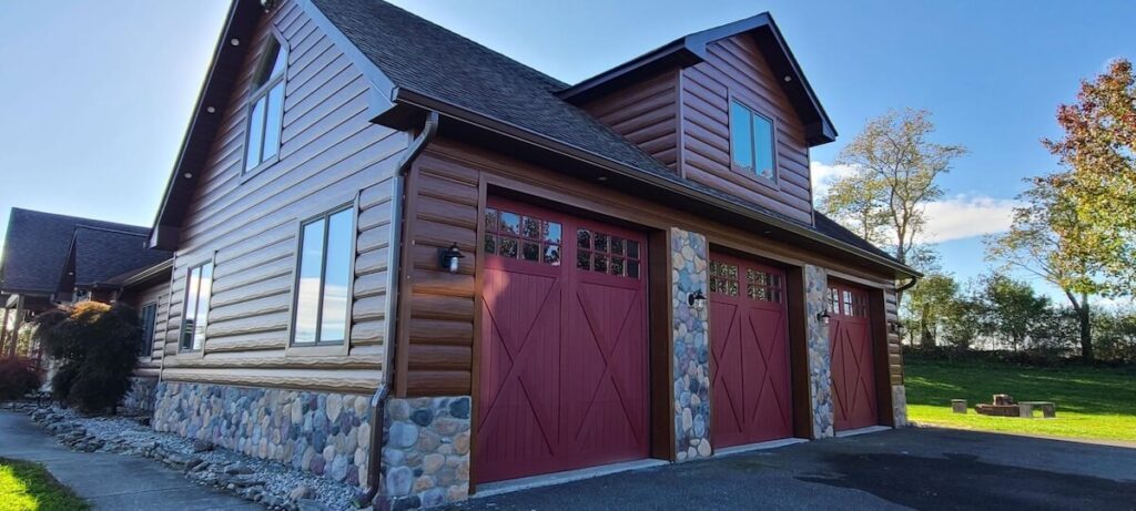 The three-car garage of a home with TruLog steel log siding and stone accents
