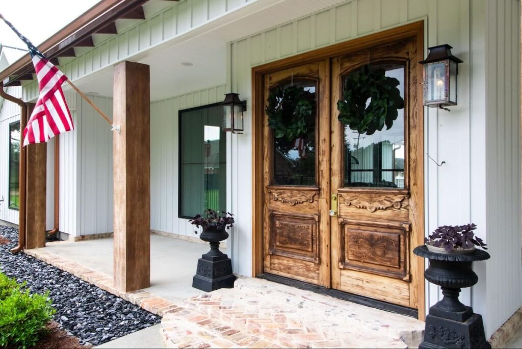 A beautiful front porch featuring large wood doors and TruLog steel board and batten siding in Matte White