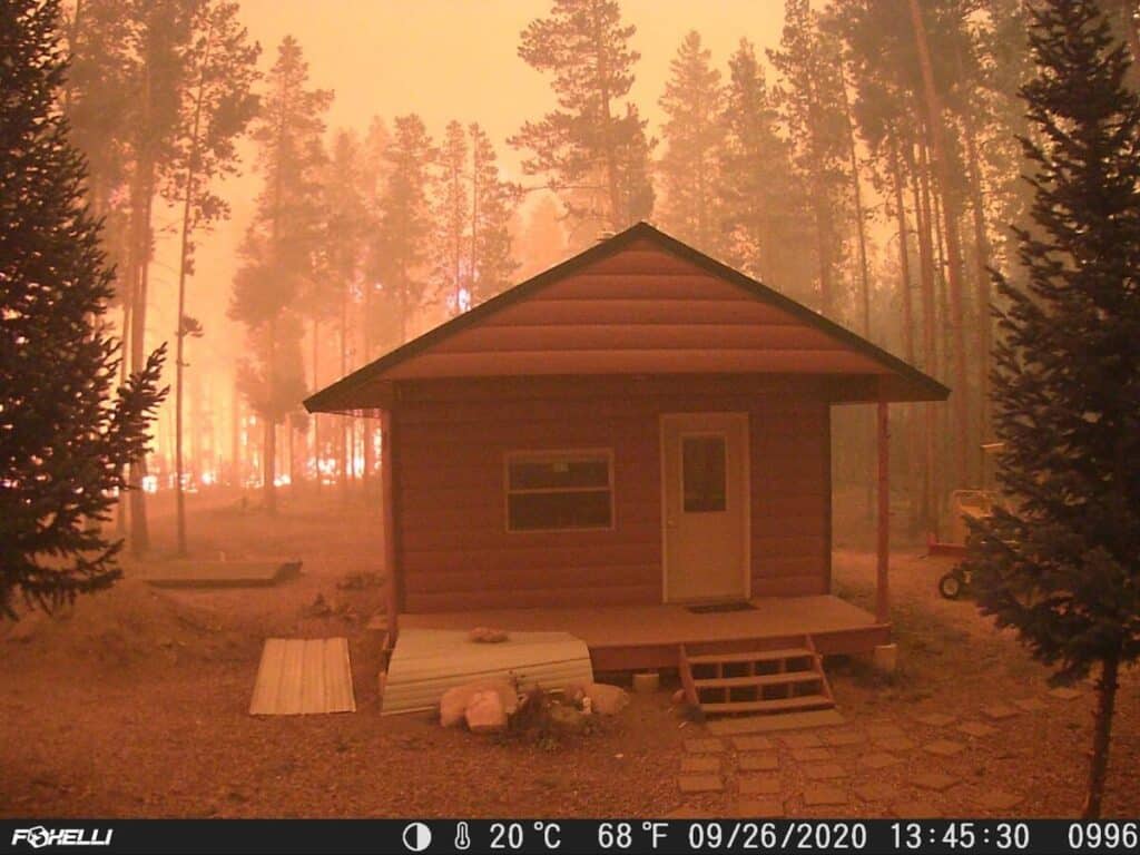 An image from a trail camera of a home with TruLog steel log siding during a wildfire
