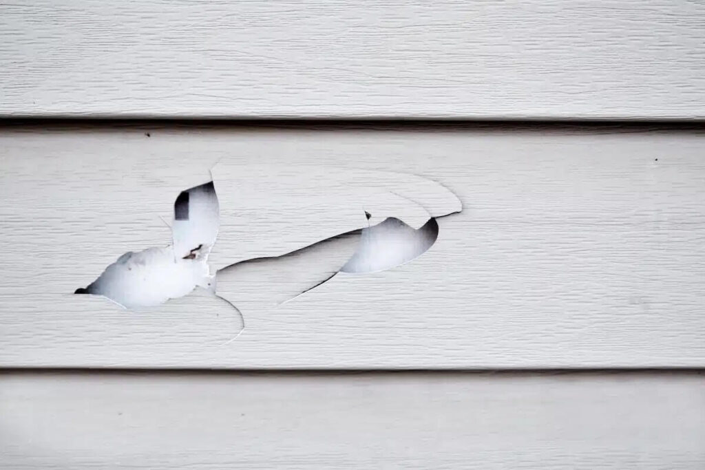 A closeup of damaged vinyl siding
