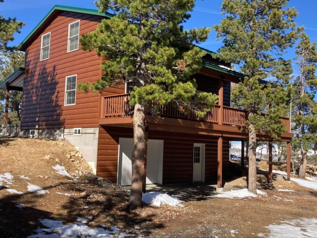 Snow melts away on a sunny winter day around a home with TruLog steel log siding