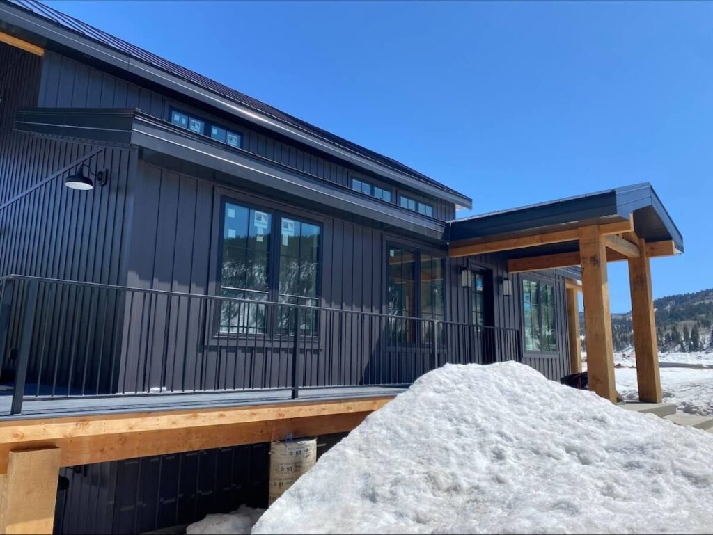 A pile of snow in front of a home with TruLog steel board and batten siding