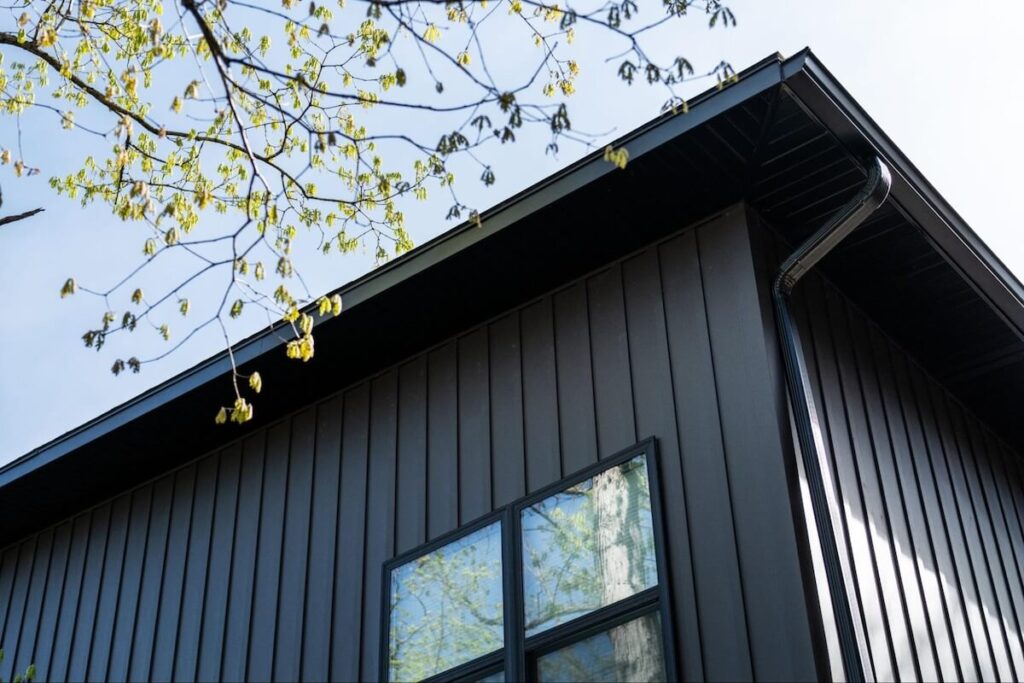 A closeup of a home's soffit, fascia, gutters, downspout, and TruLog steel board and batten siding