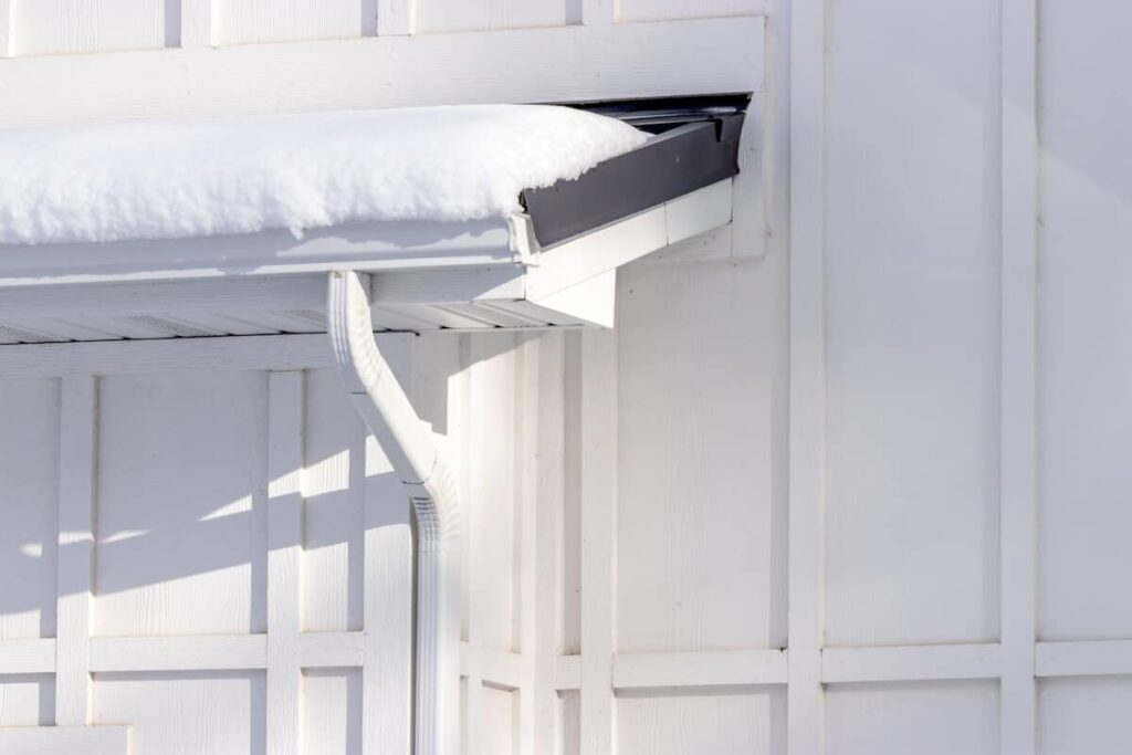 A closeup of board and batten siding and a roof overhang covered in snow