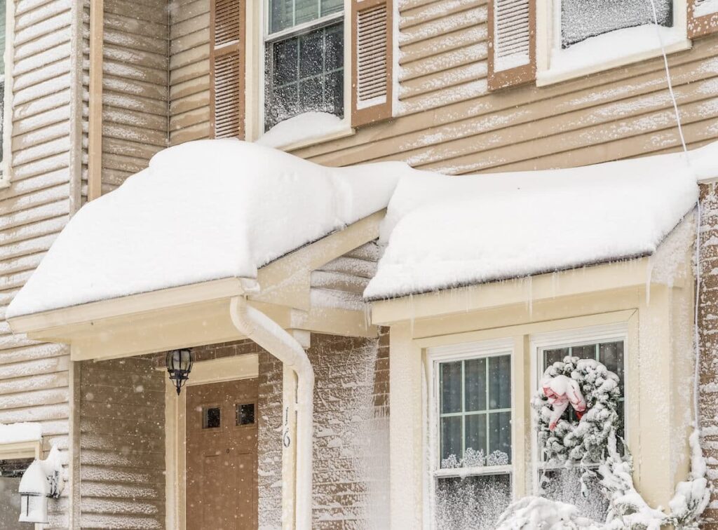 The front of a home with vinyl siding covered in snow and ice
