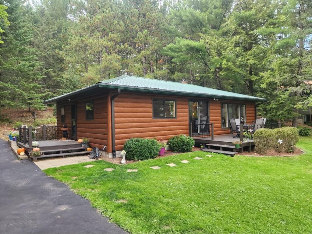 A quaint cabin surrounded by trees and cladded in TruLog steel log siding