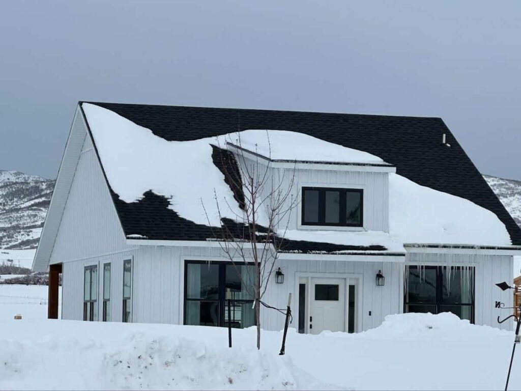 A home with TruLog steel board and batten siding surrounded by snow and covered in icicles