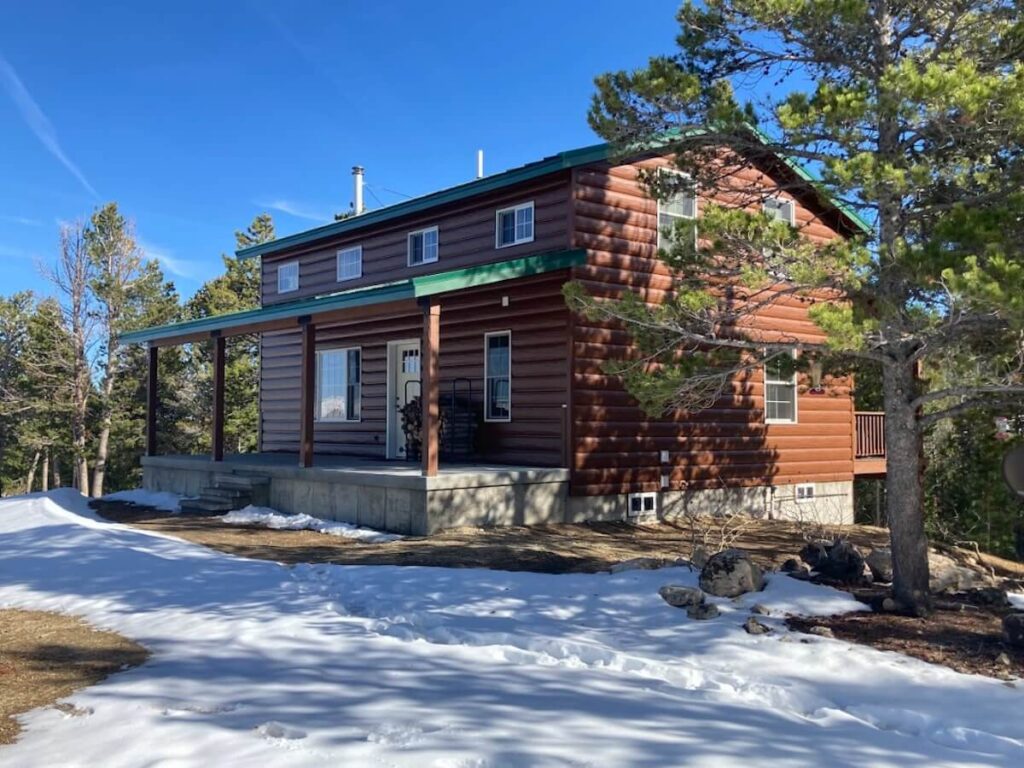 A cabin-style home designed for energy efficiency in winter with wood-look TruLog steel log siding and a green metal roof