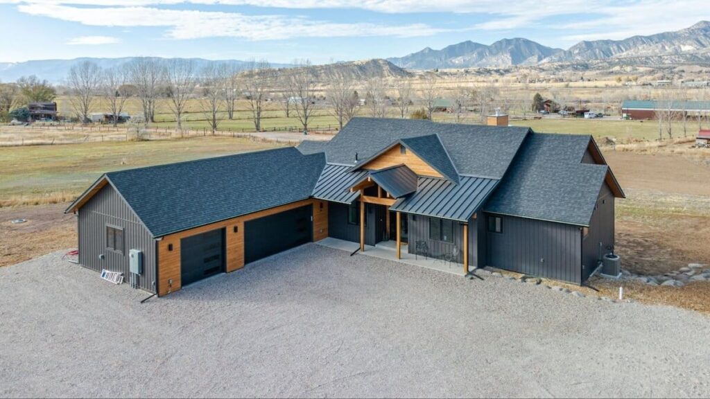 A modern farmhouse with TruLog steel board and batten siding in Dark Charcoal, wood-tone accents, and a black roof