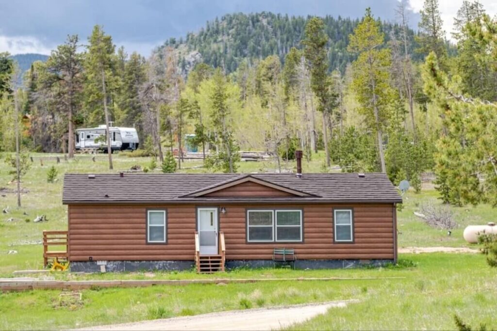 Manufactured home with brown TruLog wood-look steel siding in a mountain setting.