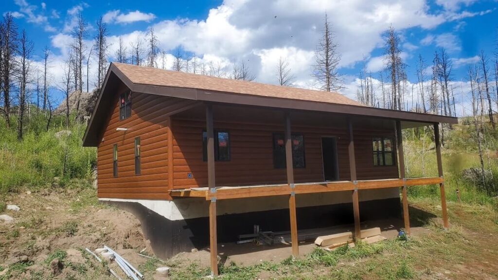 Small home with TruLog steel log-look siding in a wooded area.