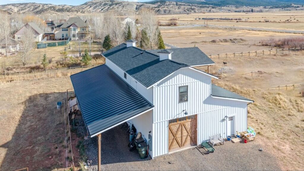 A bardominium with a rustic barn door and TruLog steel board and batten siding in Matte White