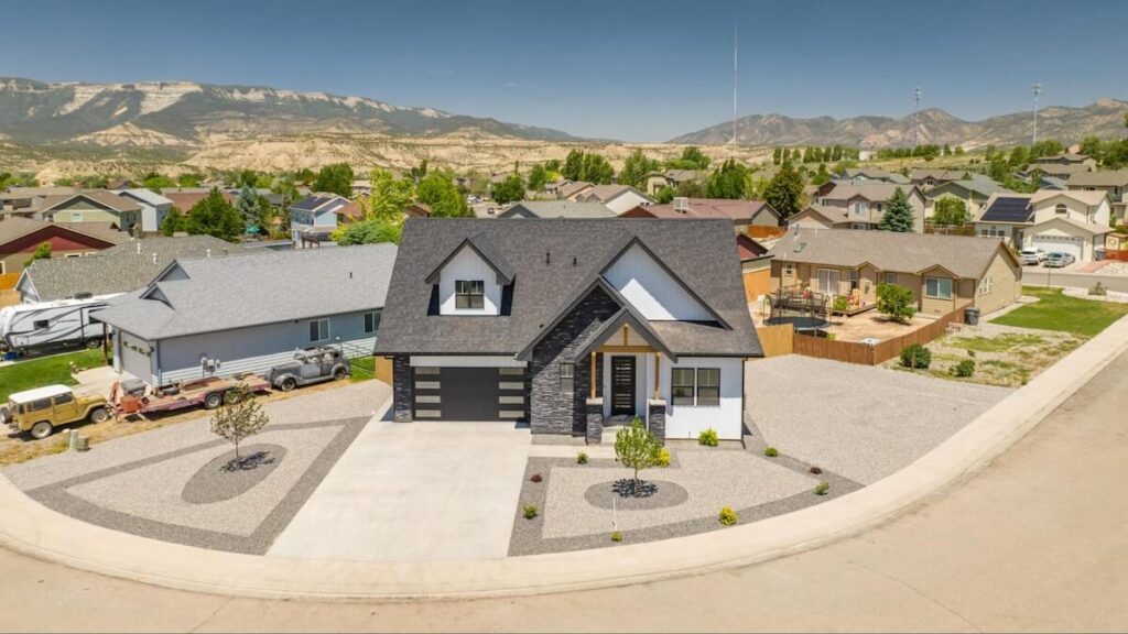 A wide aerial view of a home with a mix of exterior materials, including TruLog steel siding, wood, and stone