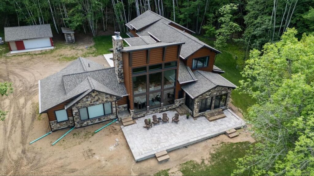 A modern home with wood-look steel siding and a stone patio with Adirondack chairs