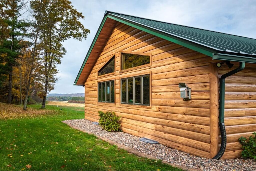 TruLog steel siding in a warm wood grain finish on a log-style home surrounded by fall foliage.