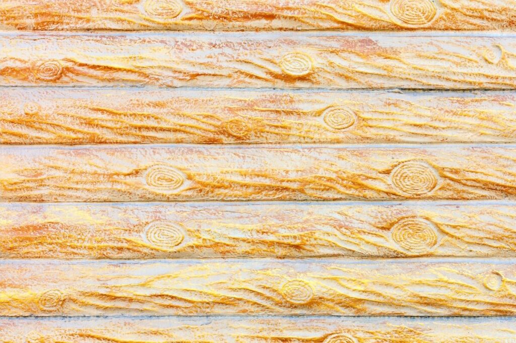 Close-up of light-colored concrete log siding with visible wood grain and knots.