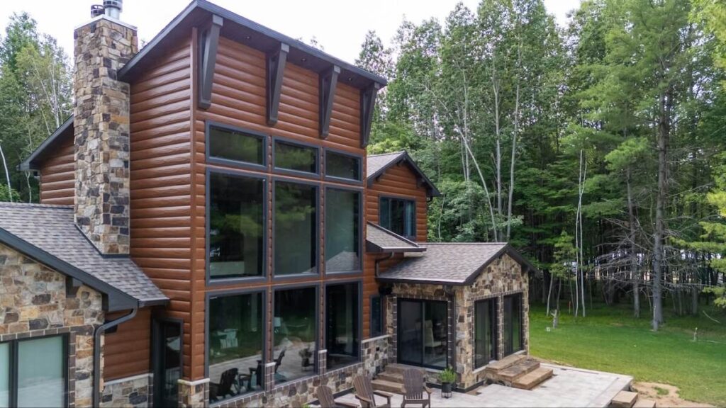 TruLog steel log siding in a cedar finish on a two-story home surrounded by trees.