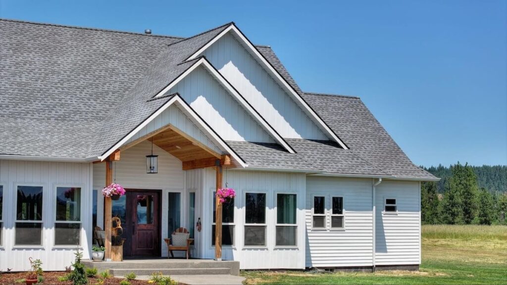White TruLog steel siding on a modern farmhouse home against a clear blue sky.