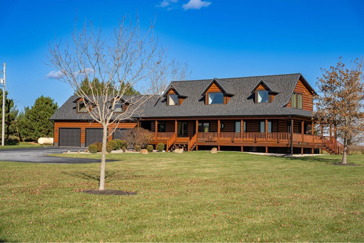 Log cabin-style home with brown wood-look TruLog steel siding and a wraparound porch.