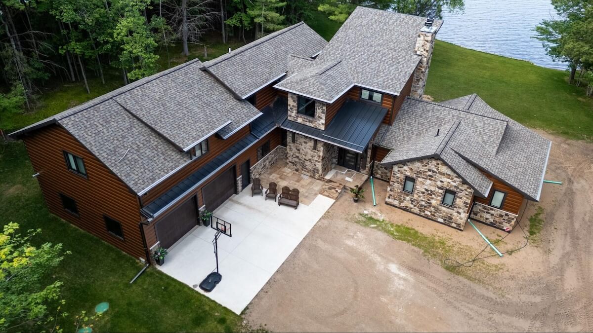 Aerial shot of a lakeside home with TruLog steel siding surrounded by a densely wooded forest.